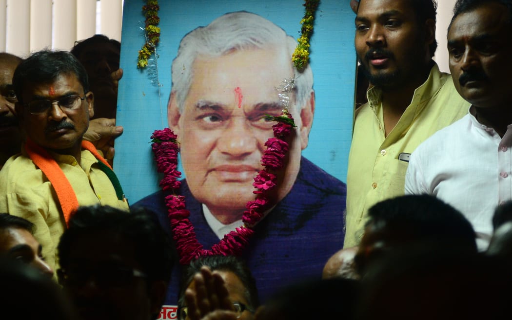 Indian Bharatiya Janata Party (BJP) workers stand next to a portrait of  former Indian Prime Minister Atal Behari Vajpayee who has died aged 93.