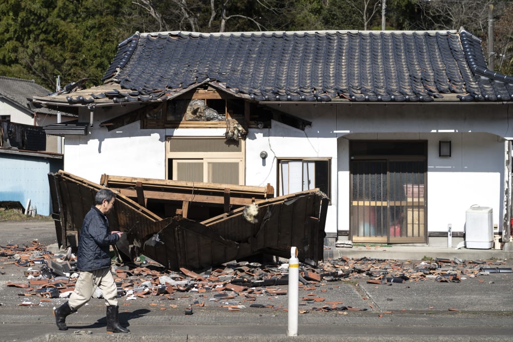 Sushi maker Akio Hanzawa walks in front of his damaged restaurant in Shiroishi, Miyagi prefecture on 17 March  2022, after a 7.3-magnitude earthquake jolted east Japan the night before.