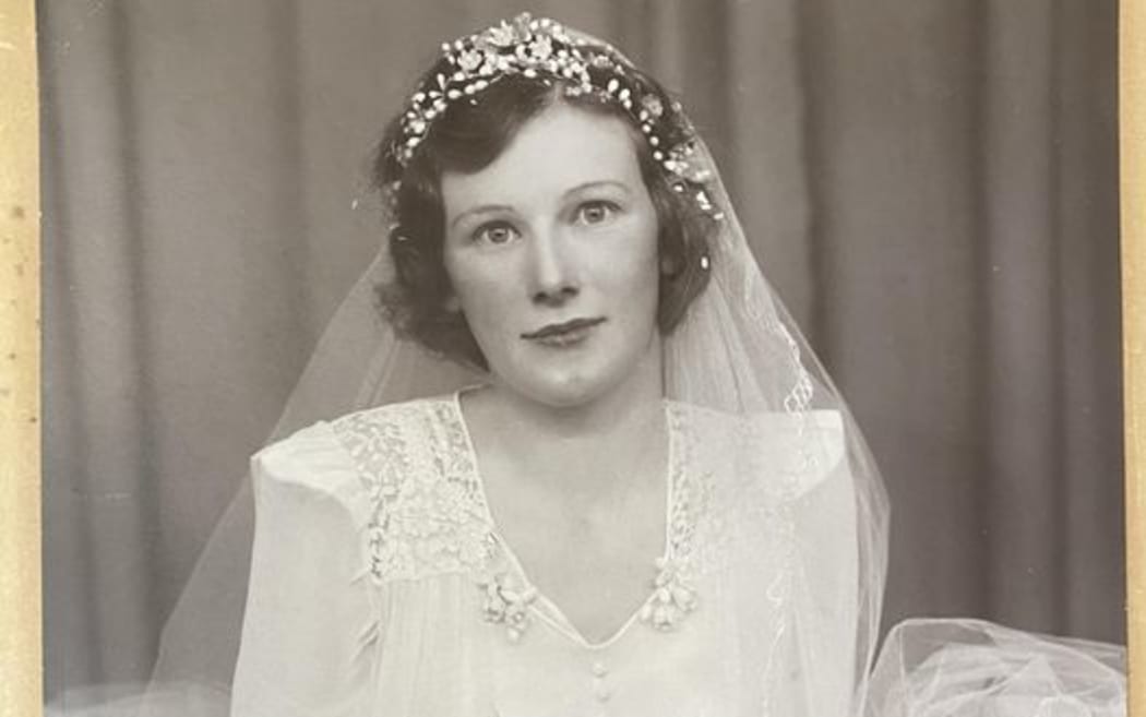 A photo of a young bride, holding a bouquet of flowers, with the words 'Titchmarsh Studio, Auckland' written in the corner.