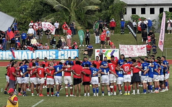 The two teams in the middle of the field in a team huddle after the game at Te'ufaiva Stadium. Tonga defeated Samoa 30-16.