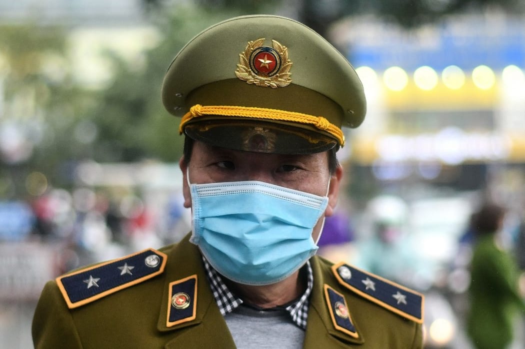 A Vietnamese policeman wearing a protective facemask stands guard at a make-shift distribution centre for free facemasks amid concerns of the novel coronavirus outbreak, in Hanoi.