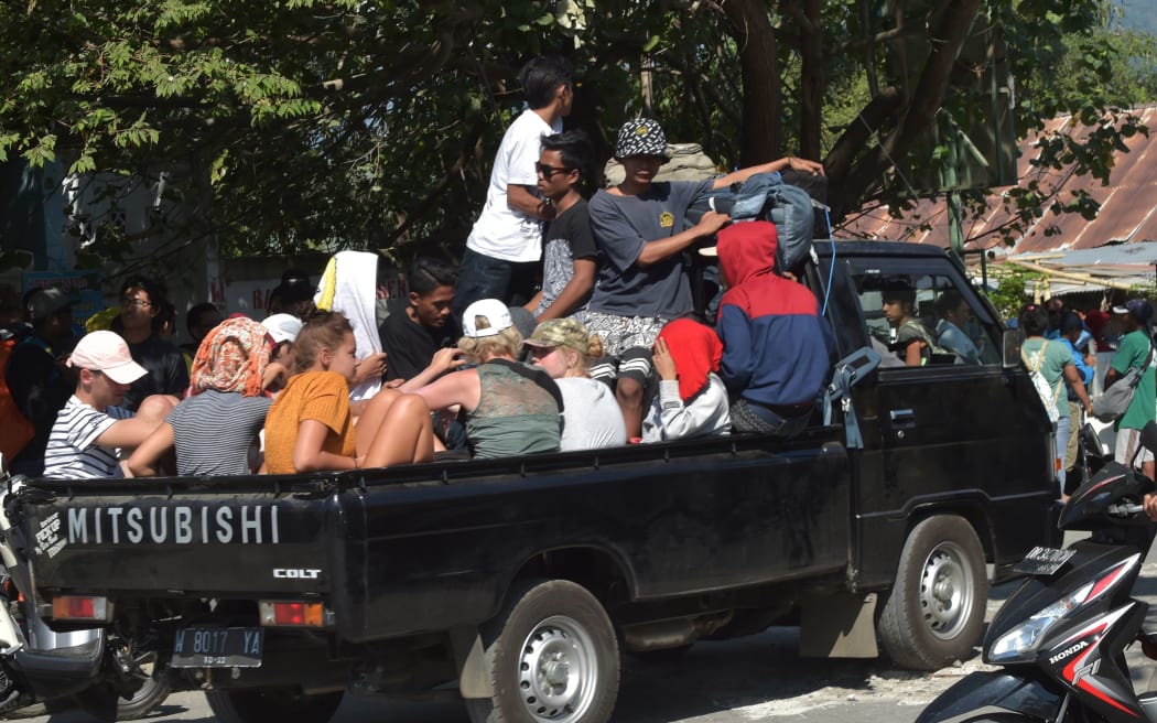 Foreign tourist and local residents ride on the back of a vehicle in Bangsal, North Lombok