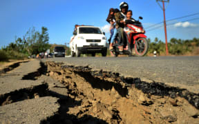 A oar car past a damage road at Kayangan subdistrict in North Lombok on West Nusa Tenggara province on August 8, 2018, three days after an earthquake hit the area.