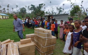 Villagers on Taveuni watch as more tents are unloaded. It is the first aid they have received since Cyclone Winston