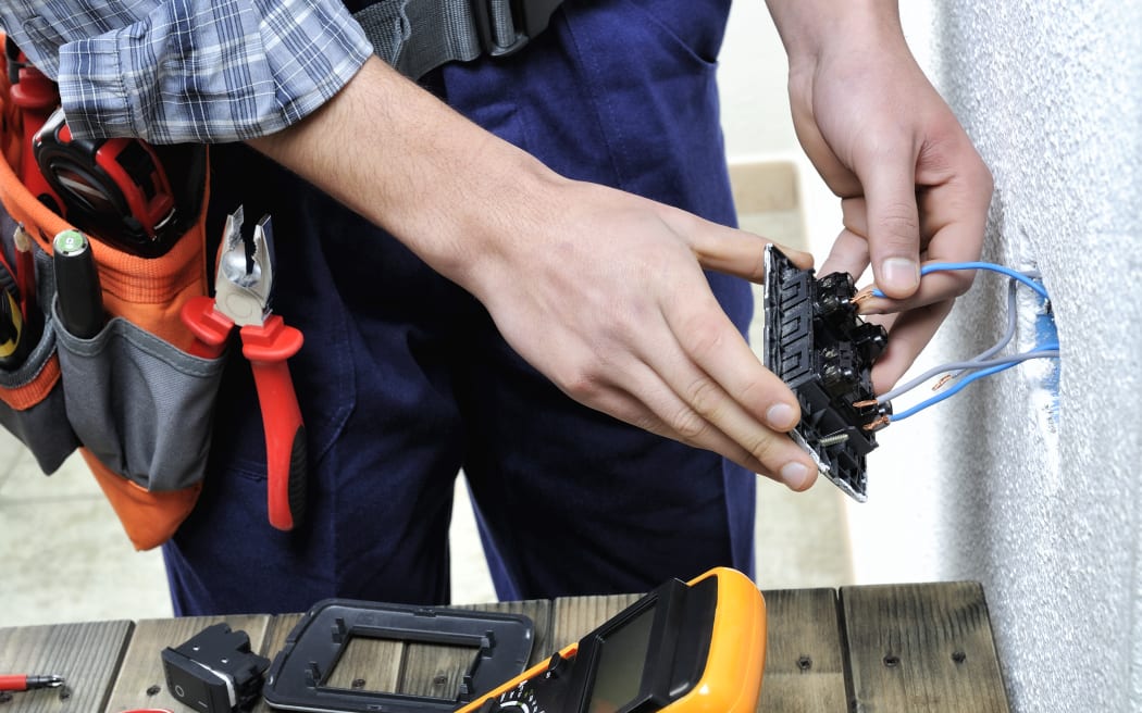 Young electrician at work on switches and sockets of a residential electrical installation.