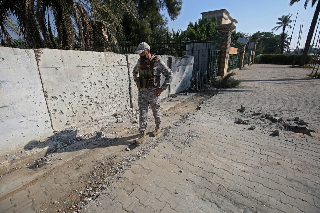A member of the Iraqi security forces inspects the damage outside the Zawraa park in Baghdad on November 18, 2020, after rockets slammed into the Iraqi capital.