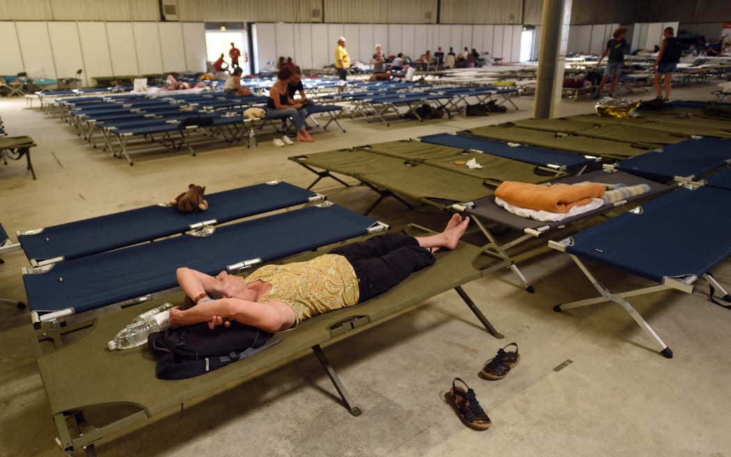 Tourists rest in an evacuation center in La Teste-de-Buch, southwestern France, on July 15, 2022. - In a context of strong heat on the southern half of the country, the firemen still face two aggressive forest fires in Gironde, with more than 5.000 hectares burned and more than 10.000 people evacuated since July 12, 2022, and fight on a "virulent" fire near Avignon southwestern France. (Photo by GAIZKA IROZ / AFP)