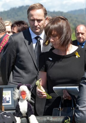 John Key (L) and his wife Bronagh lay a fern on a table holding memorabilia from the miners during a memorial service at the Omoto racecourse for the lost 29 Pike River Coal miners near Greymouth on December 2, 2010
