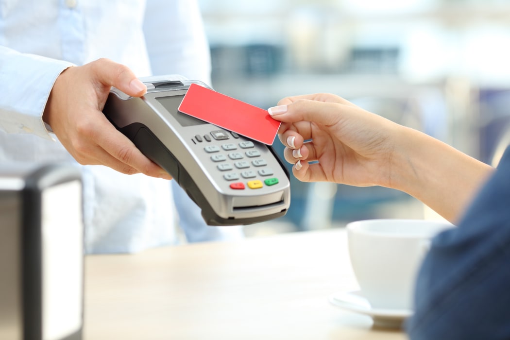 Close up of a customer hand paying with a contactless credit card reader in a bar