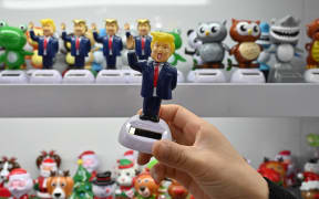 A shop owner holds a toy featuring US President Donald Trump at the Yiwu International Trade Market in Yiwu, China’s eastern Zhejiang province on April 10, 2025. US President Donald Trump abruptly paused tariffs on most countries, sparking euphoria on global markets on April 10, but upped the ante on a brutal trade war with superpower rival China. (Photo by ADEK BERRY / AFP)