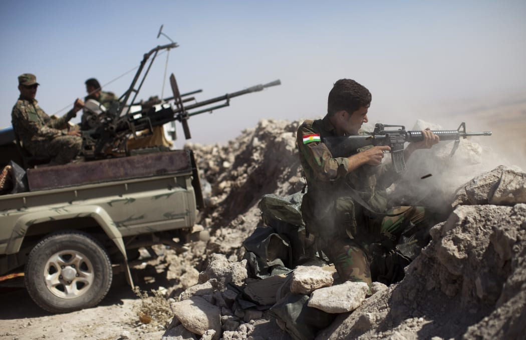 An Iraqi Kurdish Peshmerga fighter fires at Islamic State militant positions from Mount Zardak, near Mosul, in Iraq.