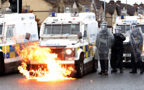 Flames lick up the front of a police vehicle as police officers are attacked by nationalist youths in the Springfield Road area of Belfast on April 8, 2021 following days of loyalist violence. -