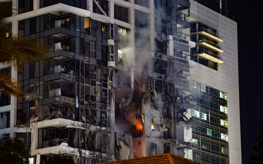 Fire and smoke rise from a building, reportedly hit by a missile fired from Iran, in central Tel Aviv on June 13, 2025. Iran fired a barrage of ballistic missiles at Israel in a counter-strike in the evening on June 13, after an unprecedented onslaught hammered the Islamic republic's top military brass and targeted its nuclear facilities and bases. (Photo by Jack GUEZ / AFP)