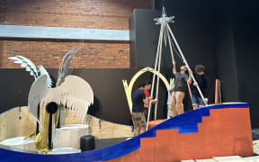 Photo depicts people trying to put a star up with a pole.