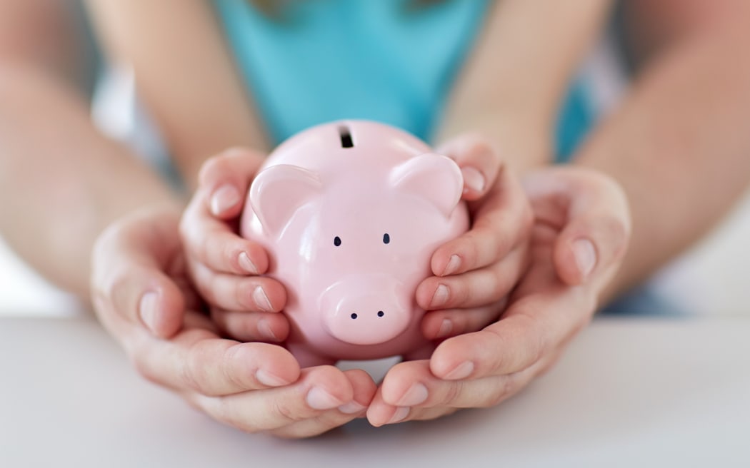 A man and a child hold a piggy bank