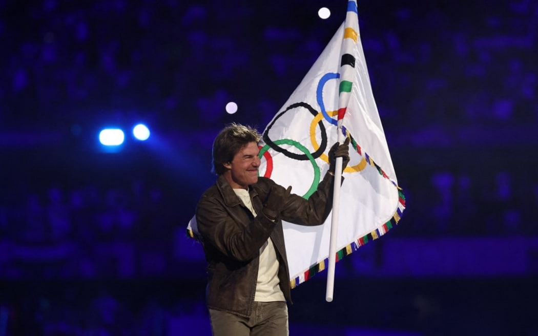 US' actor Tom Cruise waves the Olympic flag during the closing ceremony of the Paris 2024 Olympic Games at the Stade de France, in Saint-Denis, in the outskirts of Paris, on August 11, 2024. (Photo by Franck FIFE / AFP)