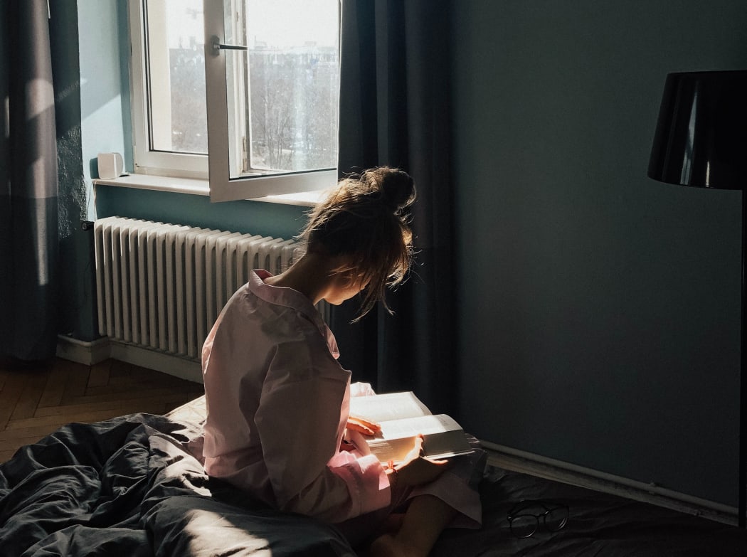 Young woman reading on a bed