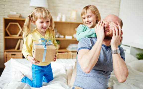 A photo of daughters giving their father a present