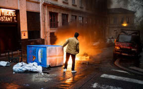 Lyon, France, 2023-04-14. A passerby stands in front of a burning barricade during the demonstration against the pension reform, after the validation of the reform by the constitutional council. Photography by Nicolas Liponne / Hans Lucas.
Lyon, France, 2023-04-14. Un passant se tient devant une barricade en feu lors de la manifestation contre la reforme des retraites, apres la validation de la reforme par le conseil constitutionnel. Photographie de Nicolas Liponne / Hans Lucas. (Photo by Nicolas Liponne / Hans Lucas / Hans Lucas via AFP)