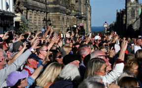 Members of the public wait to see the hearse carrying the coffin of Queen Elizabeth II, leave from from St Giles' Cathedral in Edinburgh on September 13, 2022, headed for Edinburgh airport. - Charles III on Tuesday made his maiden visit to Northern Ireland as king, as he tours all four nations of the United Kingdom before next week's state funeral of his mother Queen Elizabeth II. The casket will be flown on Tuesday evening to London, where huge crowds are expected to pay their respects as she lies in state from Wednesday evening until her funeral on Monday morning. (Photo by Oli SCARFF / AFP)