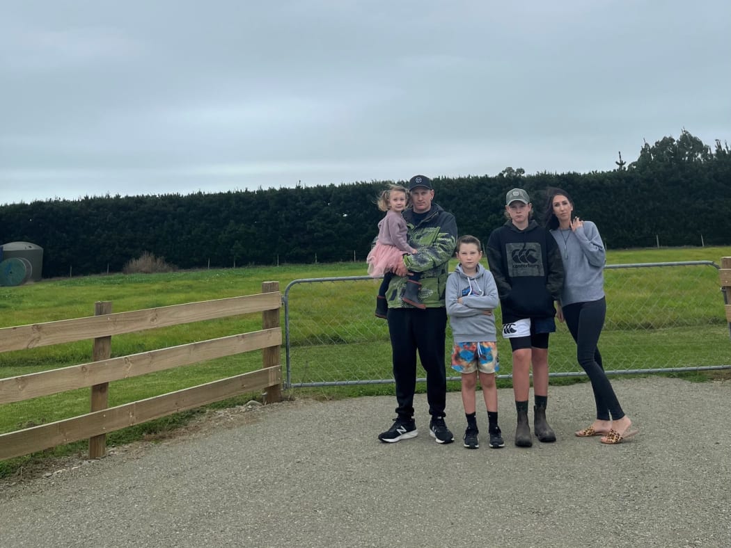 The Stockers - Poppy, Brad, Robbie, Dean, and Ellie, stand at the entrance to where their home would be by now, if not for an ongoing hold up around wastewater consents.