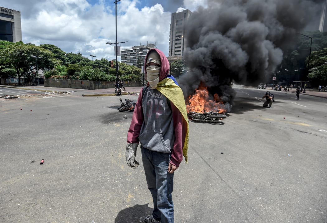 An anti-government activist stands in front of burning police bikes during a protest in Caracas against the elections for a Constituent Assembly.