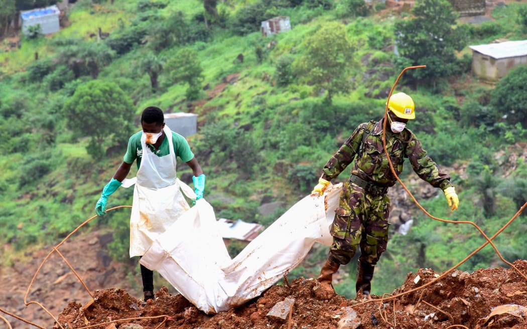 Workers remove a victim found in the mud and debris, days following the collapse of a hillside that swept away hundreds of homes in Freetown.