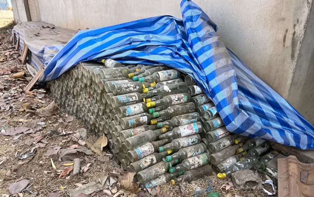 Empty bottles are piled outside the factory where the tainted alcohol was believed to have been distilled.
