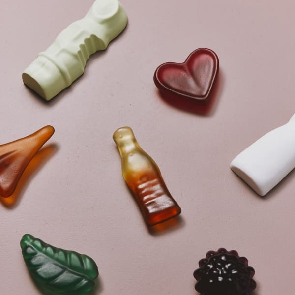 Colourful glass lolly sculptures on a pink background.