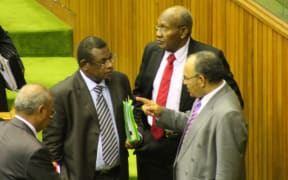 Papua New Guinea Treasurer Patrick Pruaitch (clutching folders) listens to Prime Minister Peter O'Neill (pointing finger) in parliament.