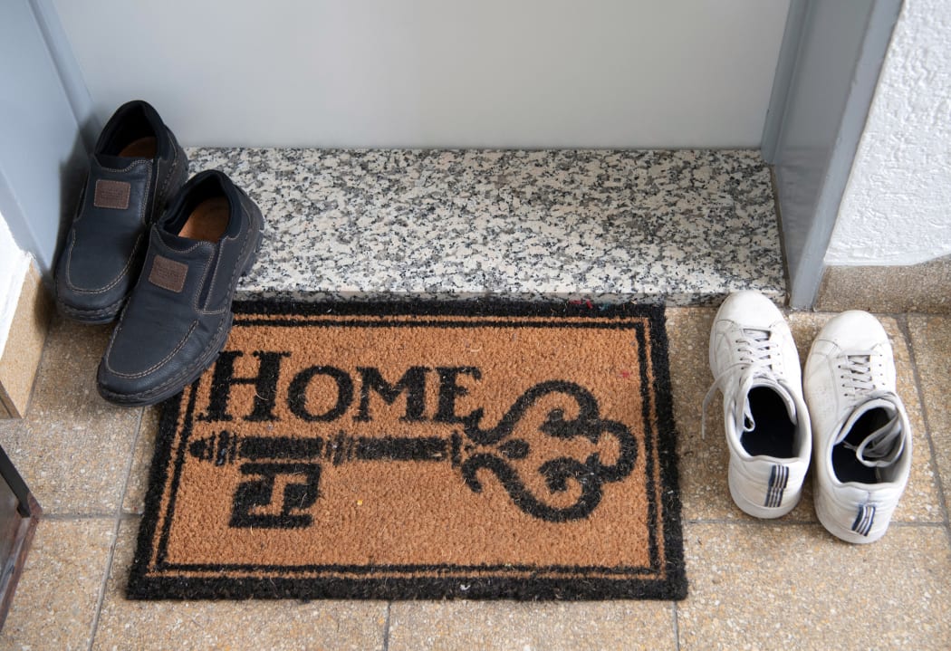 27 May 2019, Hessen, Frankfurt/Main: Two pairs of shoes stand next to a doormat with the inscription "Home". The installation of modular living elements on the upper floors of existing buildings is intended to create more living space in Frankfurt. (Too much focus from 27.05.2019) Photo: Boris Roessler/dpa (Photo by BORIS ROESSLER / DPA / dpa Picture-Alliance via AFP)