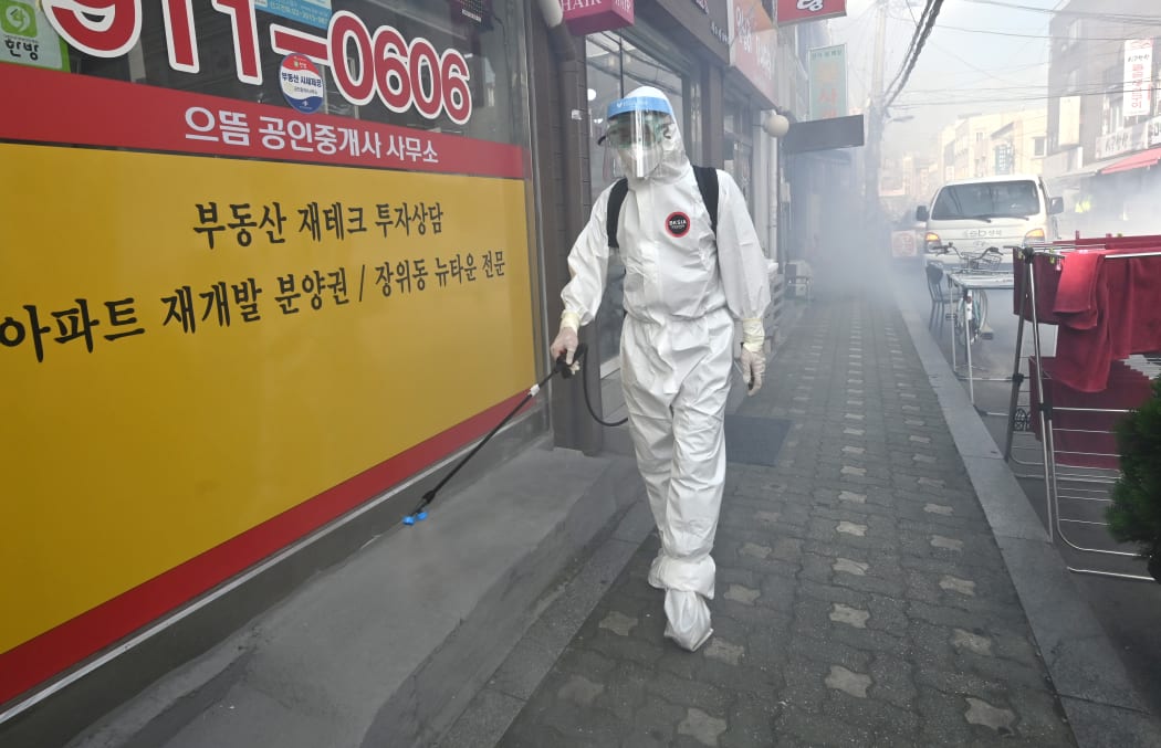 A health official wearing protective gear sprays disinfectant on the street near the Sarang Jeil Church, a new coronavirus infection cluster, in South Korea's capital Seoul.