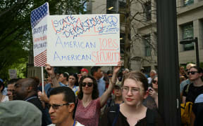 Supporters of fired US State Department workers hold signs outside the building in Washington, DC, on July 11, 2025. The US State Department began laying off more than 1,300 employees as part of President Donald Trump's campaign to massively downsize the federal government workforce. A State Department official said 1,107 members of the civil service and 246 Foreign Service employees were being informed that they were being fired. (Photo by SAUL LOEB / AFP)
