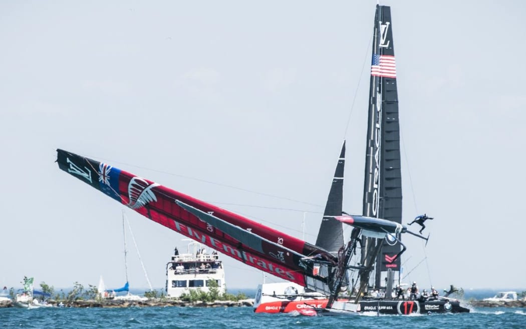Team NZ's boat goes over during practice day, and team member Glenn Ashby is sent flying.