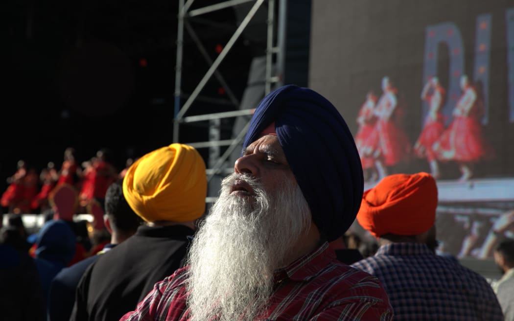 A man listens to music while dancers perform on the main stage in Aotea Square at the 2023 BNZ Auckland Diwali Festival.