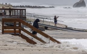 People gather on the beach to watch the large waves generated by Tropical Cyclone Alfred at Currumbin on the Gold Coast on March 6, 2025. The outer fringe of Tropical Cyclone Alfred started whipping eastern Australia on March 6, bringing drenching rains and record-breaking waves to a heavily populated region rarely hit by typhoons. (Photo by David GRAY / AFP)