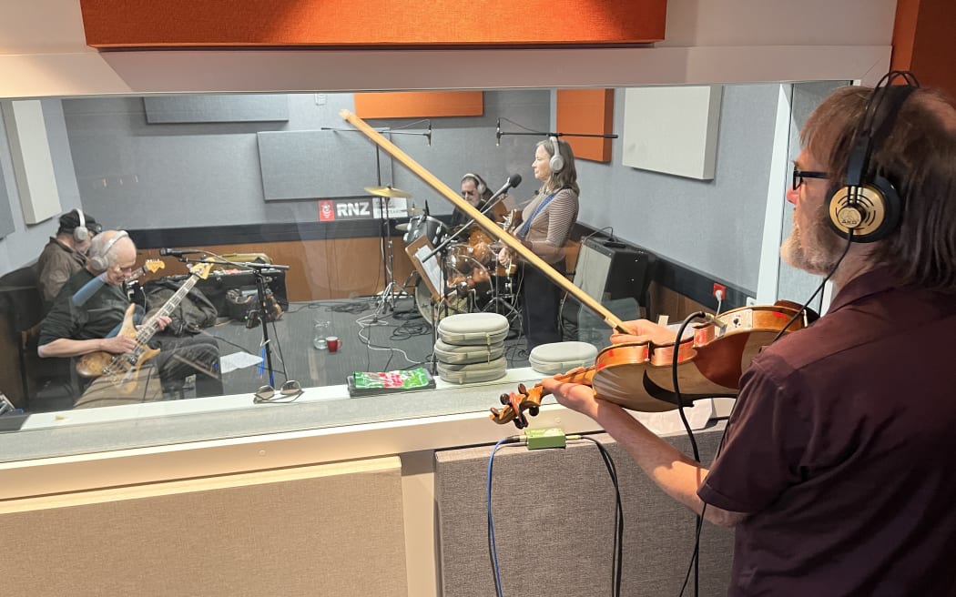 The Bats are performing in the RNZ Christchurch studio. This image is taken through the control room glass over the shoulder of the viola player.