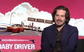 Edgar Wright in front of Baby Driver artwork