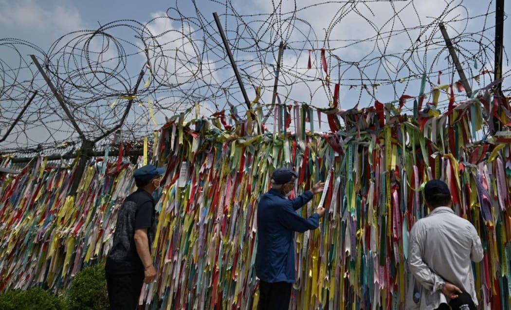 Visitors look at ribbons wishing for peace and reunification of the Korean Peninsula on a military fence at Imjingak peace park, near the Demilitarised Zone (DMZ) dividing the two Koreas in the border city of Paju on June 16, 2020. -