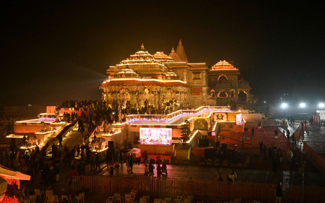 Hindu devotees gather near the illuminated Ram temple following its consecration ceremony in Ayodhya in India's Uttar Pradesh state on January 22, 2024. Prime Minister Narendra Modi said the opening of a temple on January 22, heralded a "new era" for India, at a ceremony that embodies the triumph of his muscular Hindu nationalist politics, galvanising loyalists ahead of elections this year. (Photo by Money SHARMA / AFP)