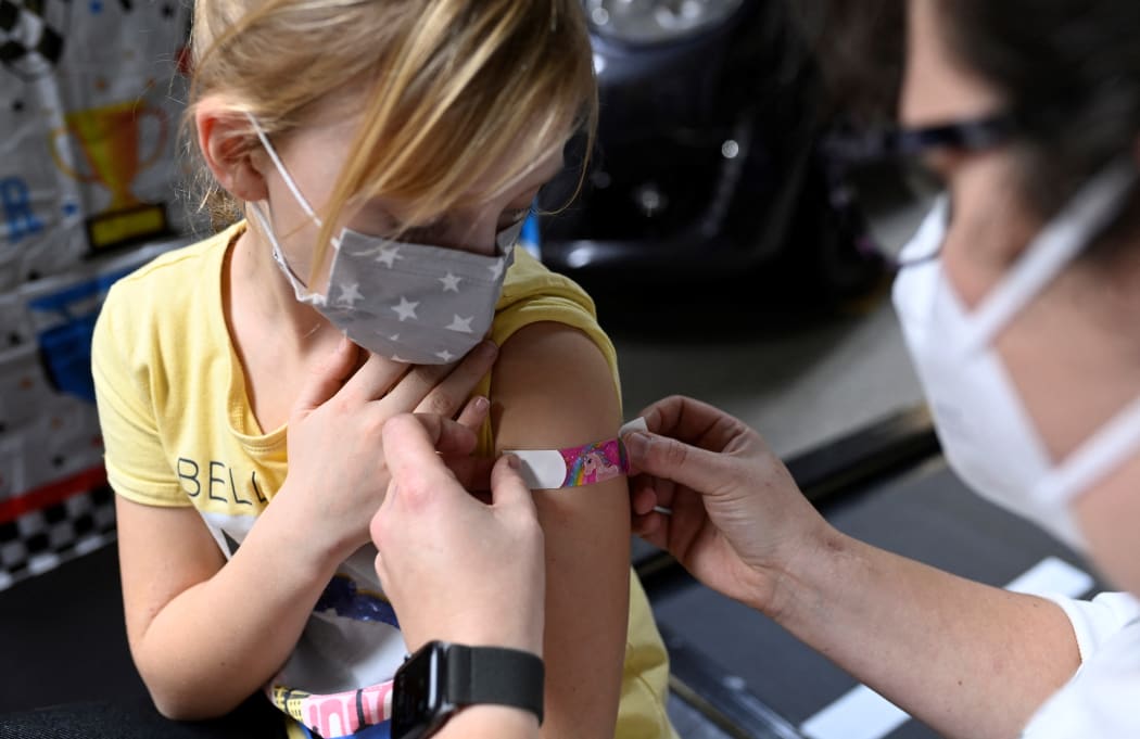 Six-year-old Hanna (left) receives a plaster after having been inoculated with the Pfizer BioNTech Covid-19 vaccine for children at a vaccination centre in Iserlohn, western Germany, on 5 January, 2022.