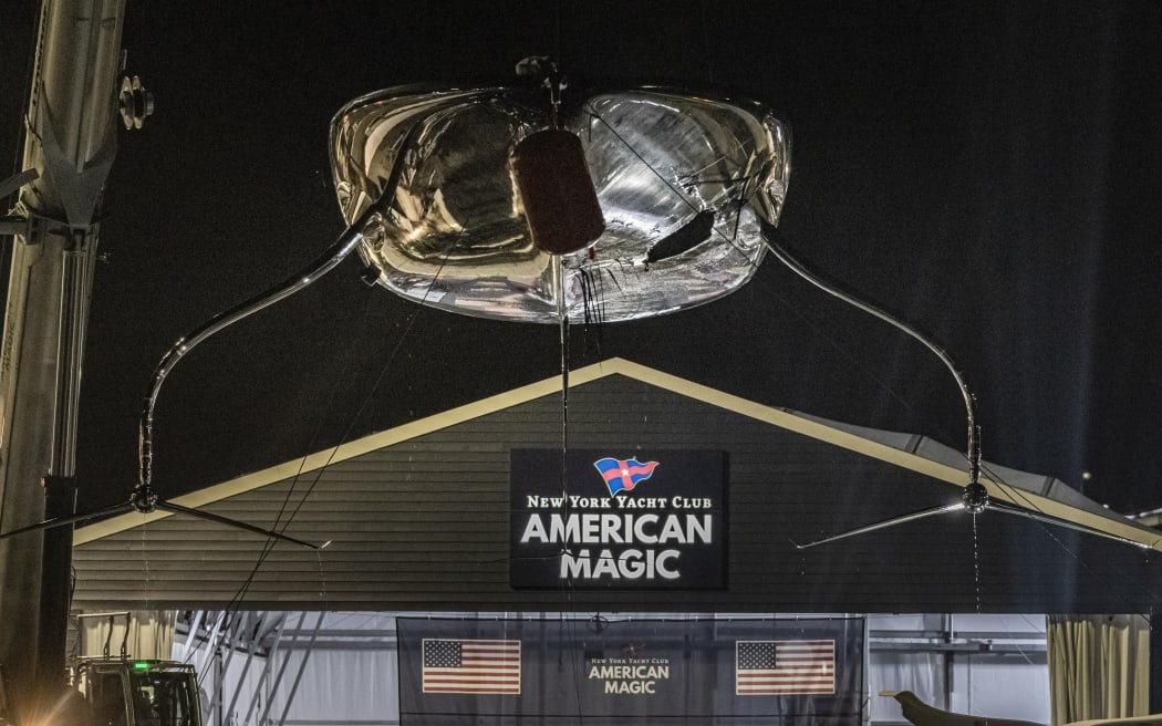 American Magic's damaged AC75 being craned back into the boat shed at the team's base in Auckland after capsizing during the America's Cup Challenger Selection Series.