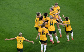 Australia's players celebrate their victory after a penalty shoot-out during the Australia and New Zealand 2023 Women's World Cup quarter-final football match between Australia and France at Brisbane Stadium in Brisbane on August 12, 2023. (Photo by WILLIAM WEST / AFP)