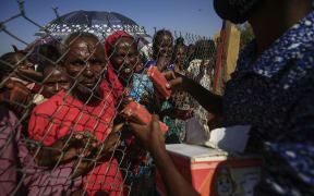 Ethiopian refugees who fled fighting in the Tigray Region receive snacks at the Village 8 border reception center in Sudan's eastern Gedaref State, on November 20, 2020.