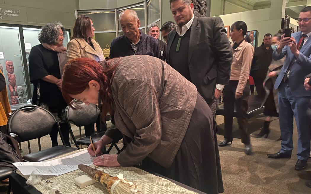 Rachel Wesley signing documentation for the return of the taiaha named 'Maungārongo'.