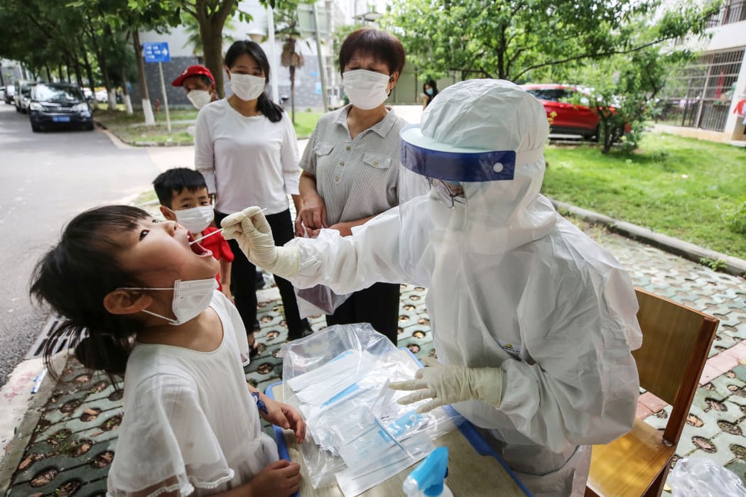 This photo taken on May 16, 2020 shows a medical worker taking a swab sample from a child to be tested for the COVID-19 coronavirus, in a street in Wuhan, in China's central Hubei province.