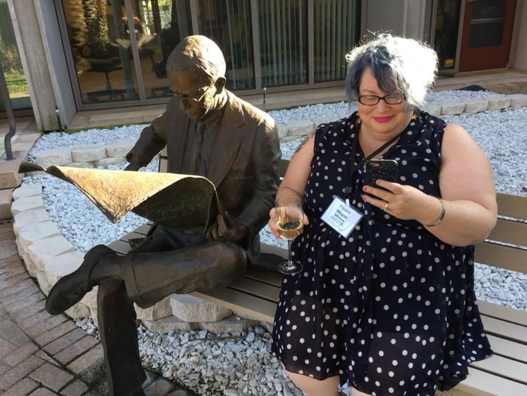 RNZ's acting Digital Editor, Megan Whelan sitting next to a statue of Nelson Poynter.