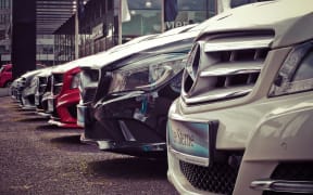 Cars lined up for sale in a car dealership yard.