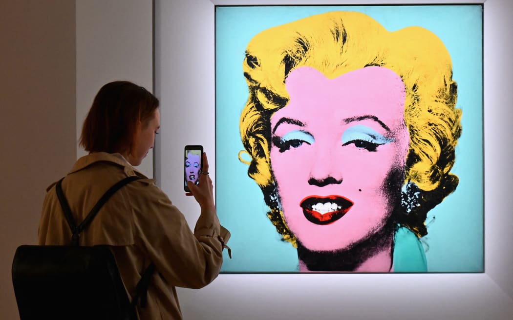 A woman takes a photo of Andy Warhol's 'Shot Sage Blue Marilyn' during Christie's 20th and 21st Century Art press preview at Christie's New York on April 29, 2022 in New York City.