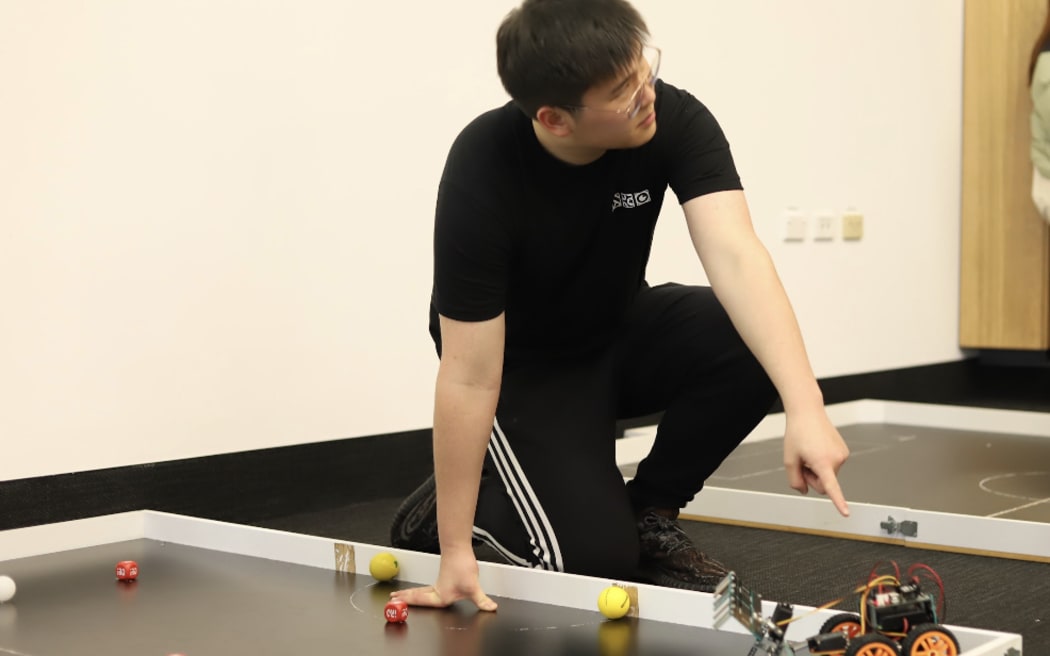 Kevin Guo points to small robot.